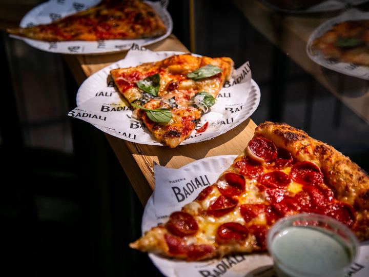 Slices of pizza on Pizzeria Badiali paper plates